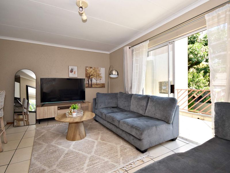 A well-maintained living room featuring tiled flooring and a large sliding glass door that provides access to an outdoor balcony area.