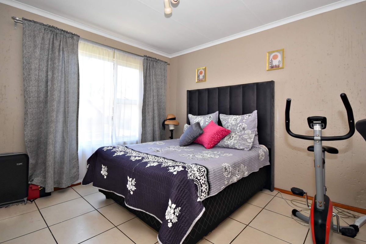 A functional bedroom featuring tiled flooring, neutral wall finishes, and a coved ceiling, providing a comfortable space with natural light.