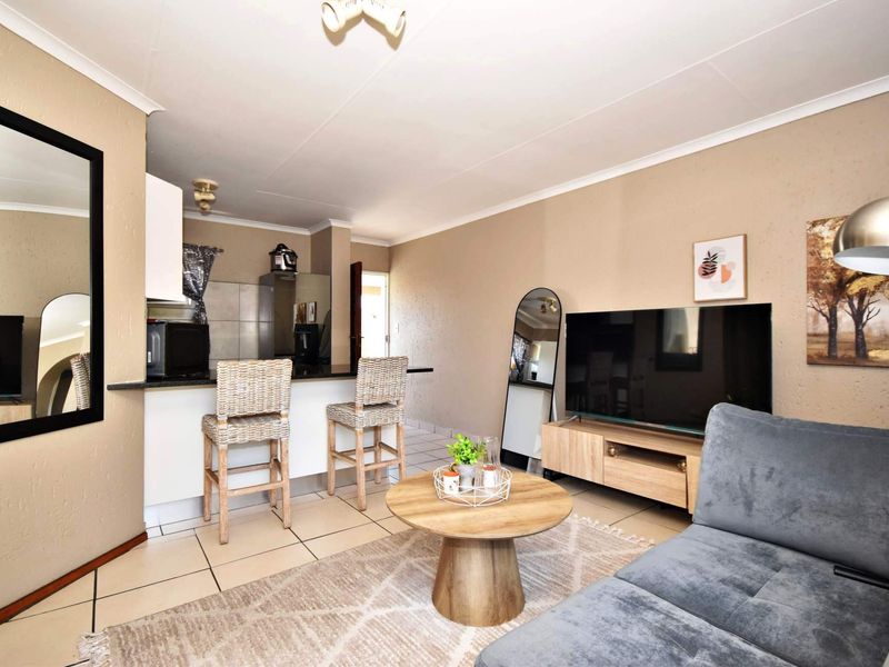 Open plan living area featuring a breakfast bar, tiled flooring, and neutral wall finishes, seamlessly connecting the kitchen and lounge space.
