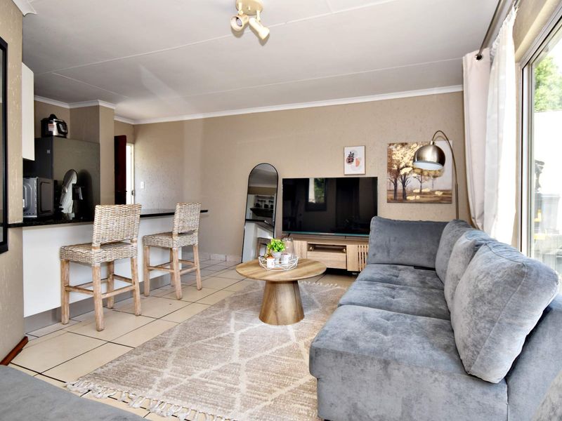 Open-plan living area featuring tiled flooring, a breakfast bar, and a sliding glass door providing natural light.