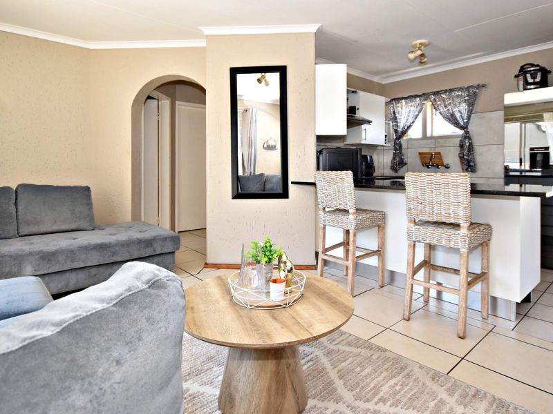 Open-plan living area featuring a breakfast bar, tiled flooring, and a functional kitchen with granite countertops and built-in cabinetry.