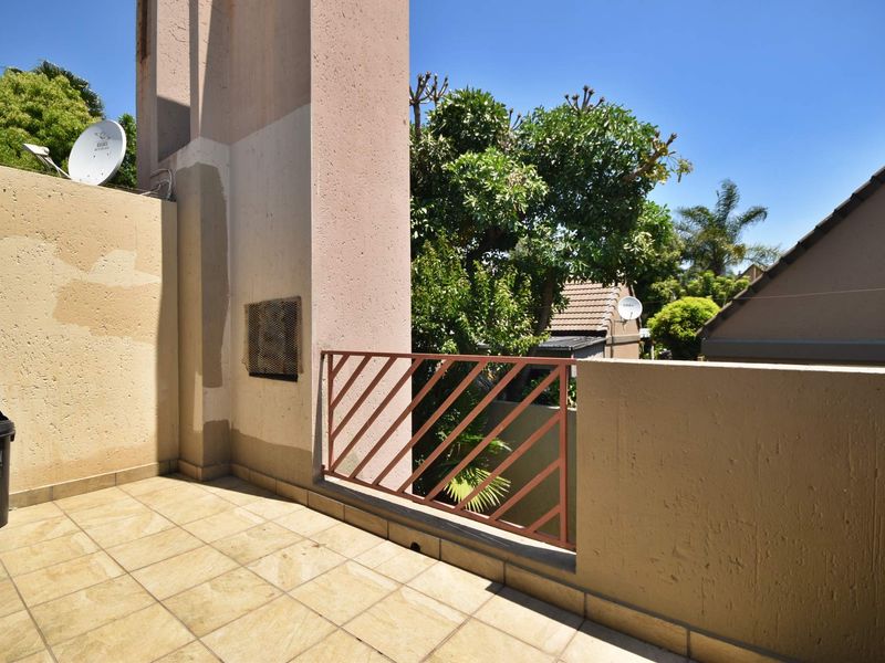 An open-air balcony featuring tiled flooring and a metal balustrade, requiring minor cosmetic updates to the wall finishes.