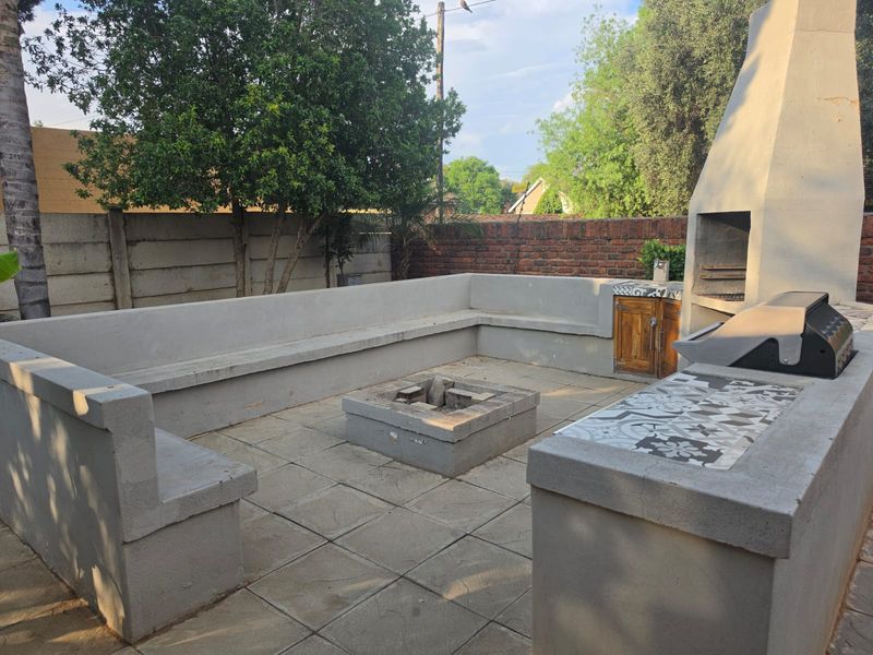 Outdoor entertainment area featuring a built-in braai, concrete fire pit, and integrated bench seating, perfect for social gatherings.