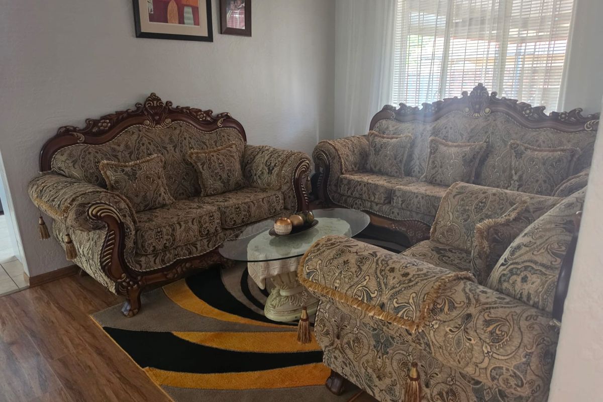 A comfortable living room featuring laminate flooring and natural light filtered through venetian blinds, providing a functional and inviting space.