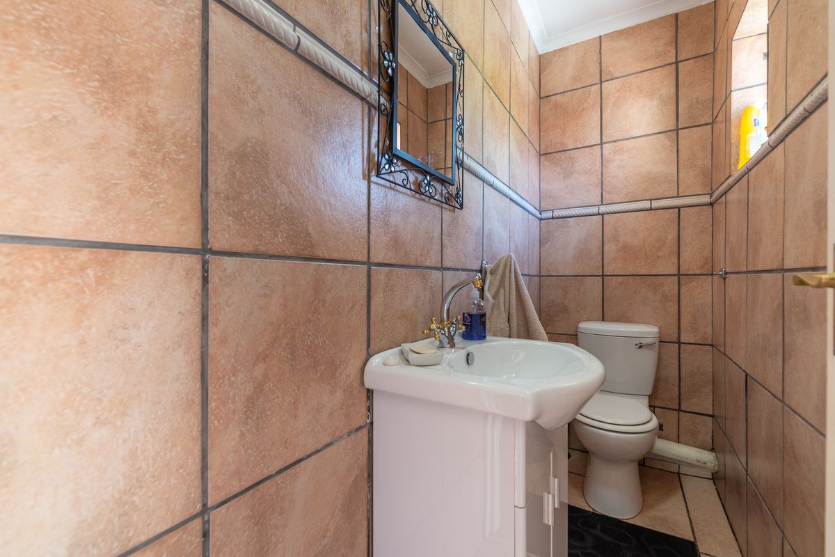 A compact guest bathroom featuring full-height ceramic wall tiling, a pedestal basin, and a standard toilet.