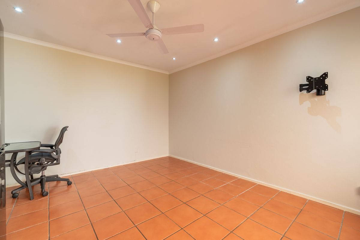 A spacious, empty bedroom featuring ceramic floor tiles, a ceiling fan, recessed lighting, and a wall-mounted television bracket.