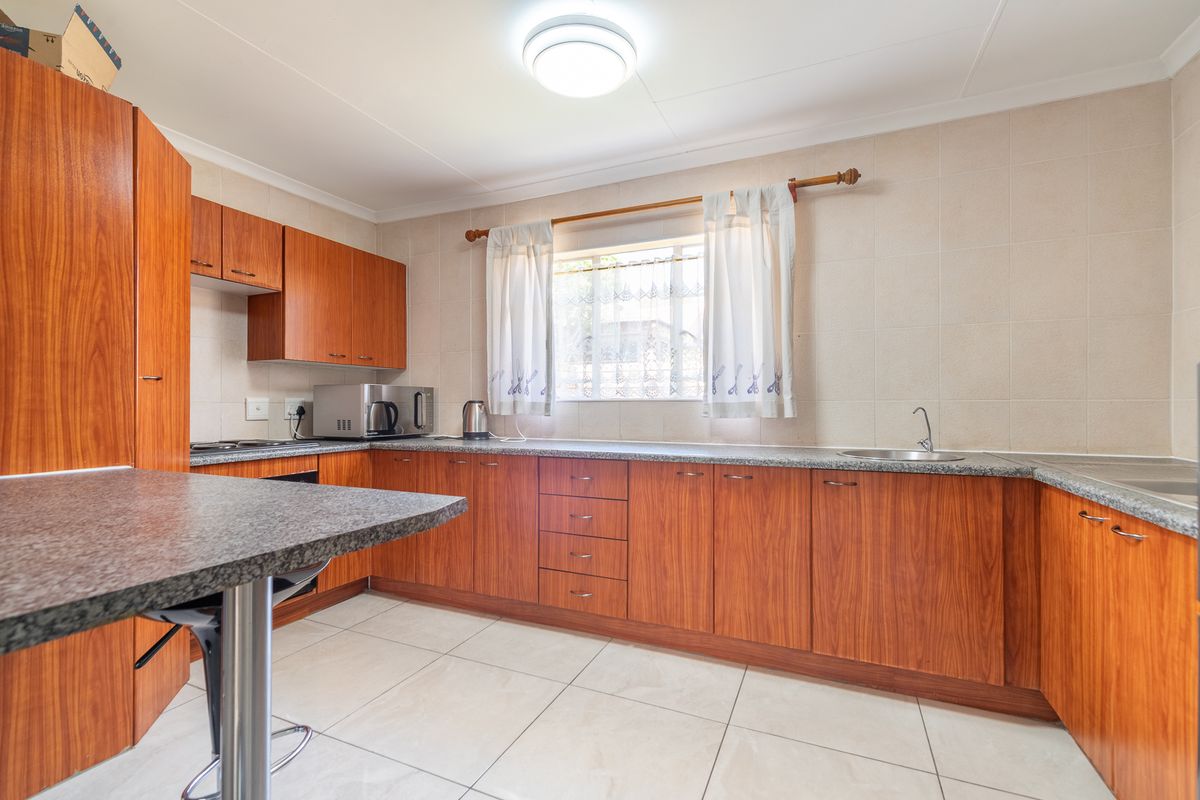 Functional kitchen featuring wood-finish cabinetry, granite countertops, tiled backsplash, and ceramic flooring, offering a practical layout for daily meal preparation.