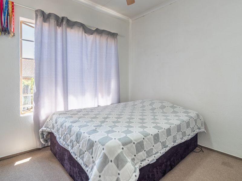 A standard bedroom featuring carpeted flooring and a ceiling fan, providing a functional and neutral space ready for personalization.