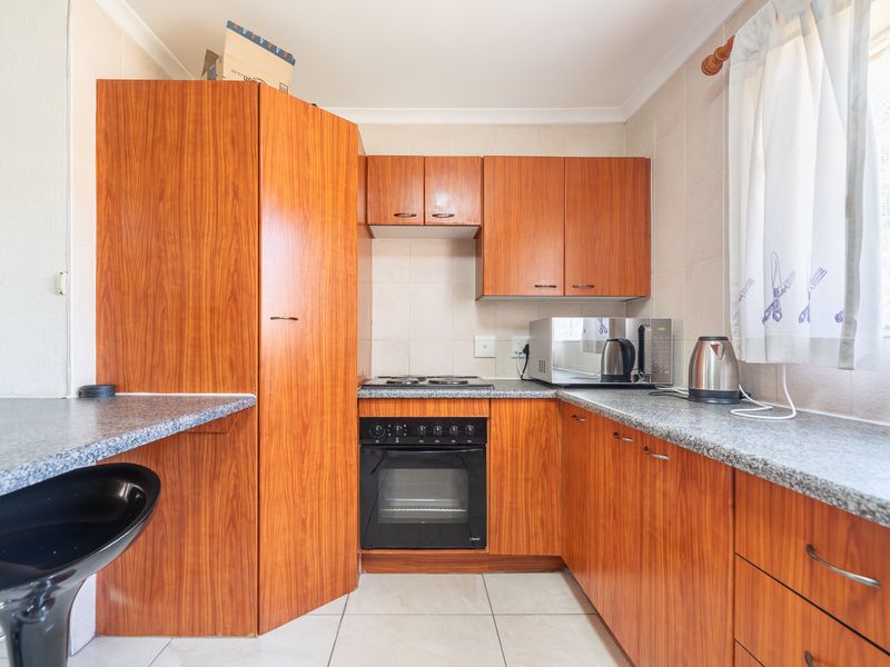 A functional kitchen featuring wood-finish cabinetry, granite-look laminate countertops, a built-in oven, and a tiled backsplash.