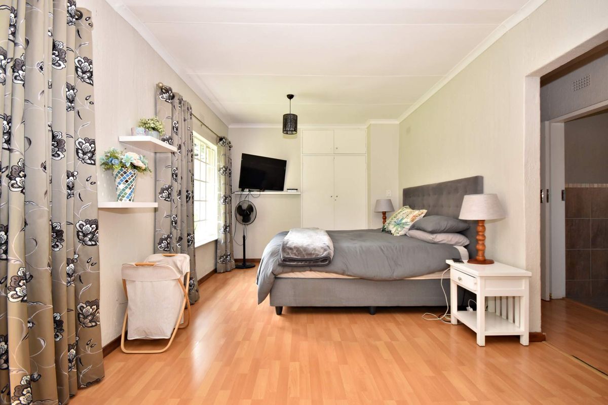 A well-lit bedroom featuring laminate flooring, built-in cupboards, and a coved ceiling, providing a comfortable and functional living space.