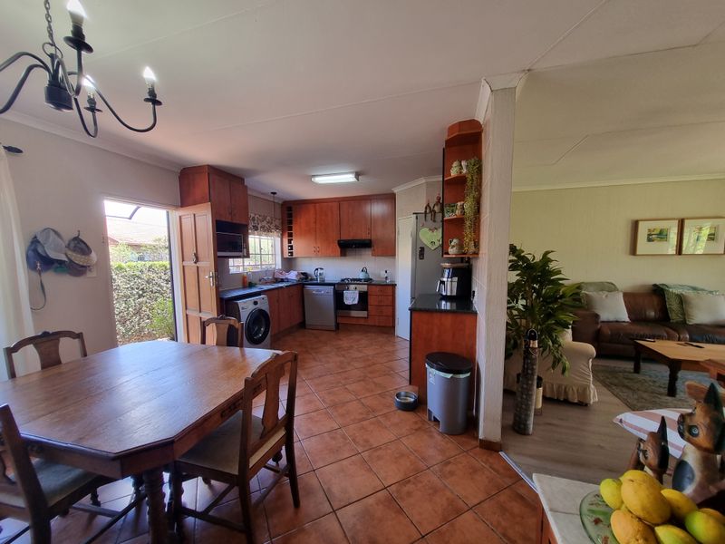 Open plan kitchen and dining area featuring wooden cabinetry, tiled flooring, and direct access to the exterior, offering a functional layout for daily living.