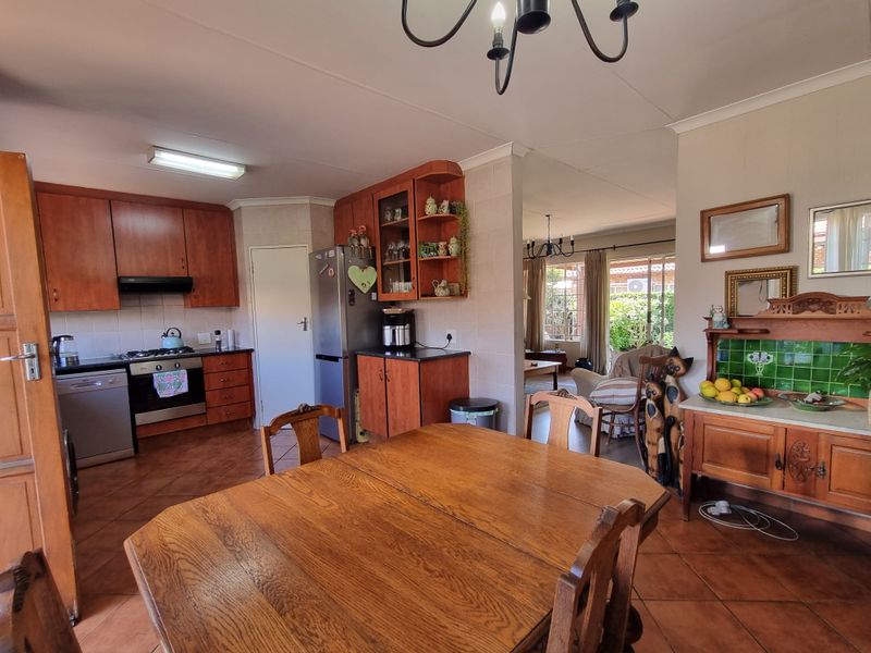 Open-plan kitchen and dining area featuring wooden cabinetry, tiled flooring, and direct access to the adjacent living space and outdoor patio area.