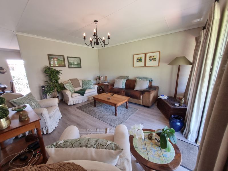 A comfortable and well-maintained living room featuring light-toned laminate flooring, neutral wall finishes, and a classic wrought iron chandelier.