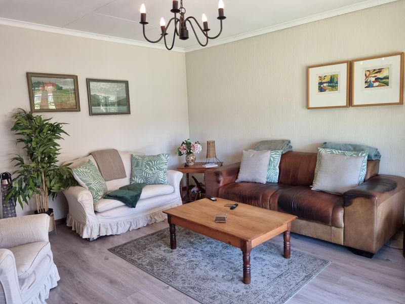 A comfortable living room featuring laminate flooring and a classic chandelier, providing a neutral and inviting space for relaxation.