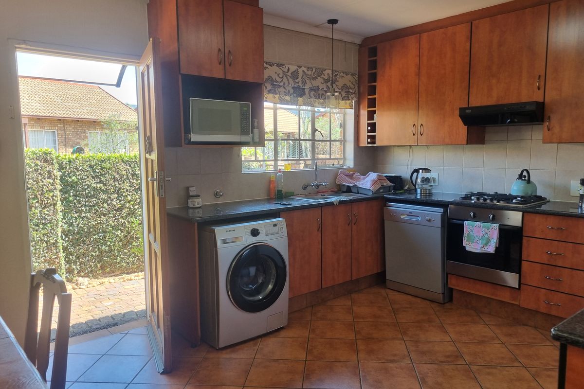 Functional kitchen featuring wood-finish cabinetry, gas hob, built-in oven, and direct access to the outdoor area, with tiled flooring and backsplash.