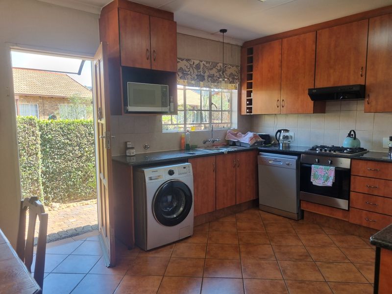 Functional kitchen featuring wood-finish cabinetry, gas hob, built-in oven, and direct access to the outdoor area, with tiled flooring and backsplash.