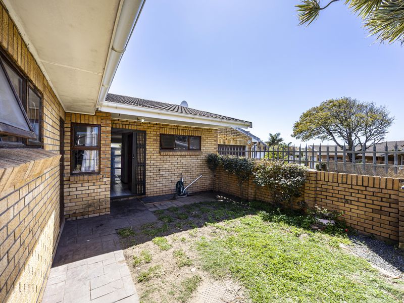 A private rear courtyard featuring face brick walls, a paved walkway, and a small garden area, providing a functional outdoor space.