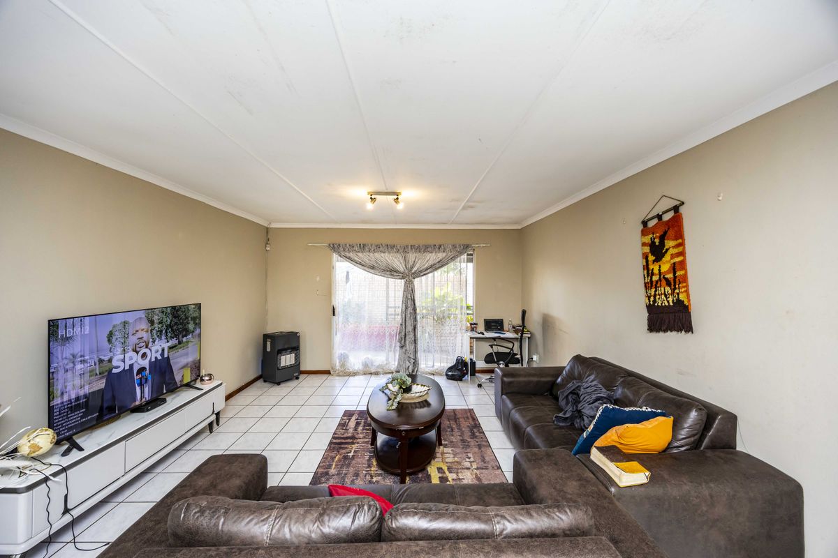 Spacious living room featuring tiled flooring and a sliding glass door leading to the exterior, with visible ceiling maintenance required.