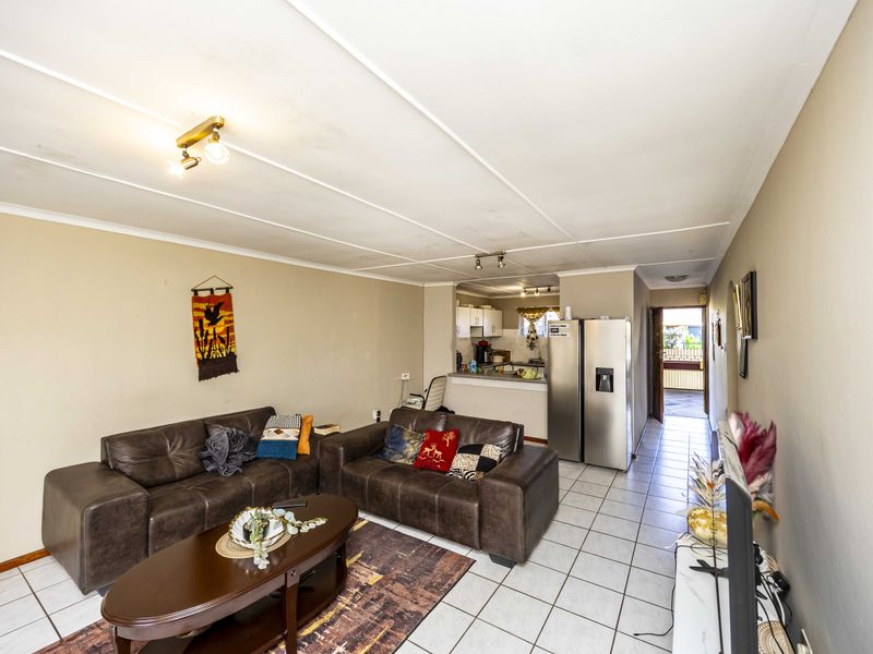 Open plan living area featuring tiled flooring and a connected kitchen space with built-in cabinetry.