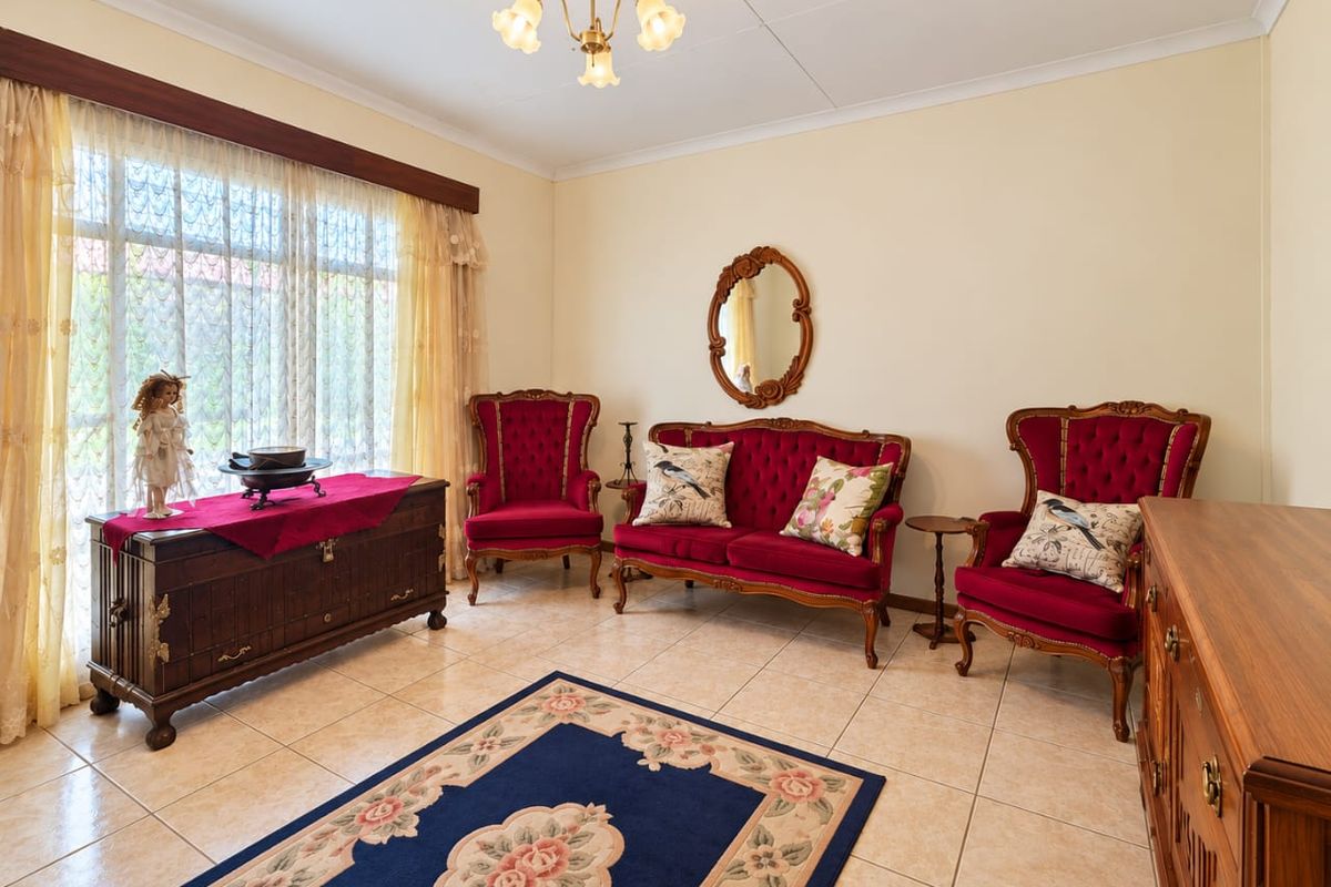 A well-maintained living room featuring neutral tiled flooring, coved ceilings, and a large window that allows for ample natural light.