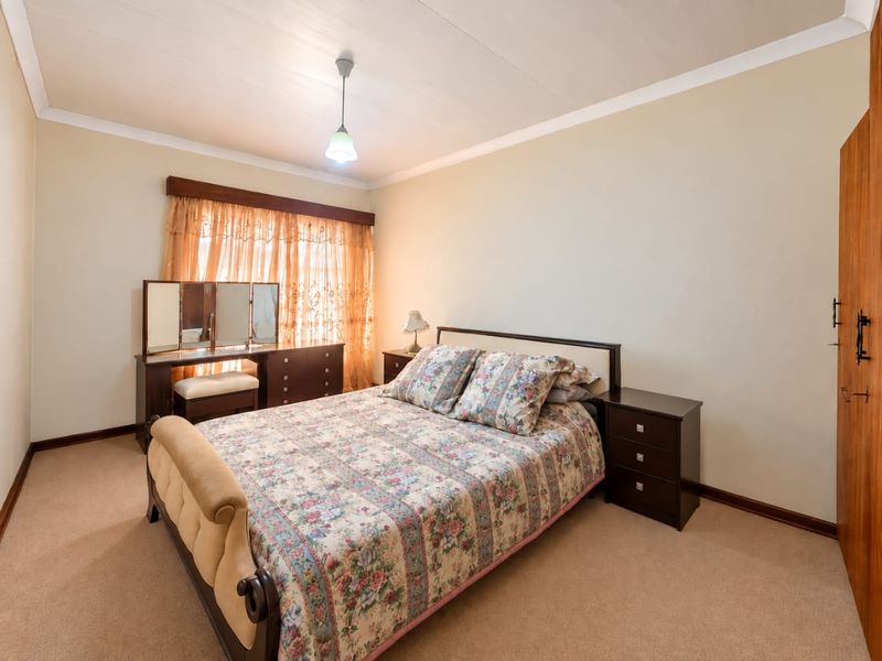 A well-maintained bedroom featuring neutral walls, carpeted flooring, and a built-in wardrobe, offering a comfortable and functional living space.