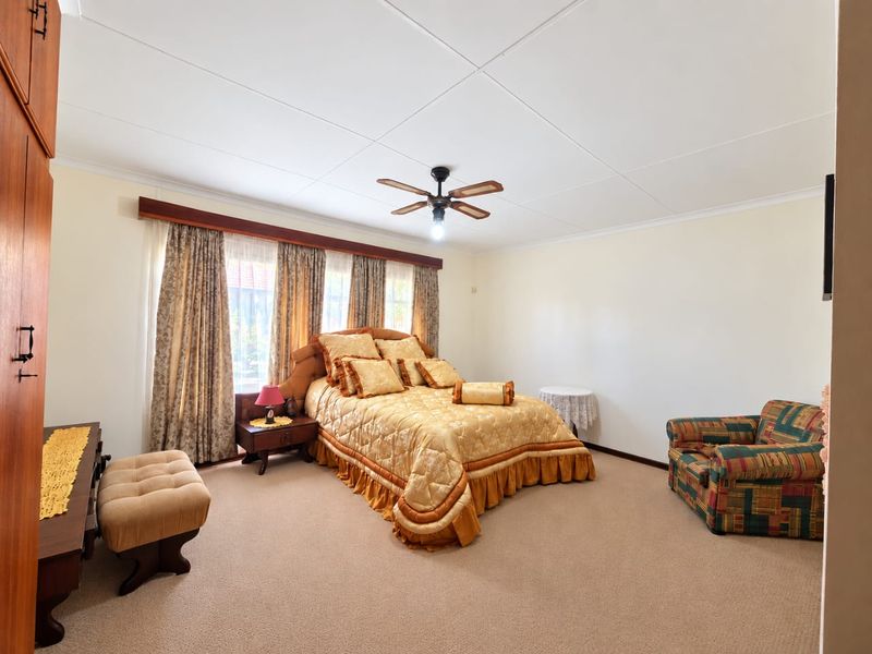Spacious bedroom featuring neutral carpet flooring, a ceiling fan, and built-in wardrobe storage.