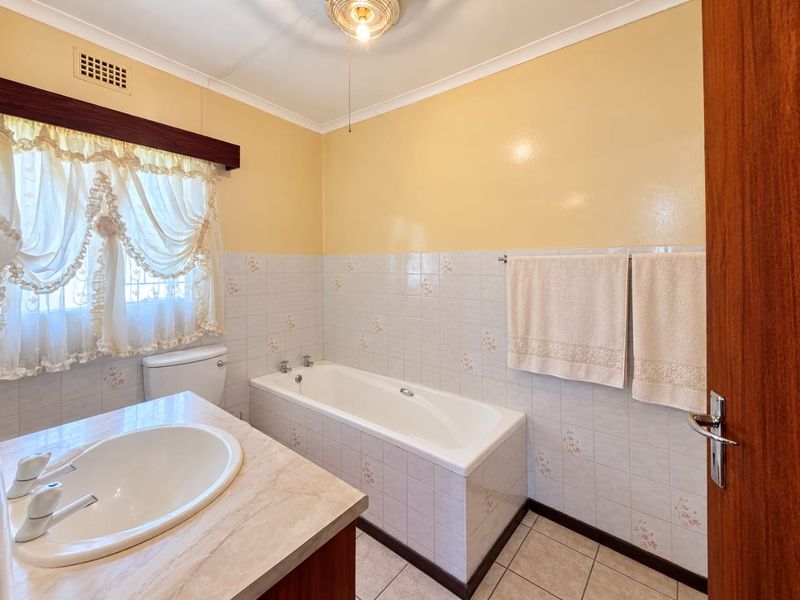 A functional bathroom featuring a built-in vanity with a drop-in basin, a standard bathtub, and tiled wall finishes.