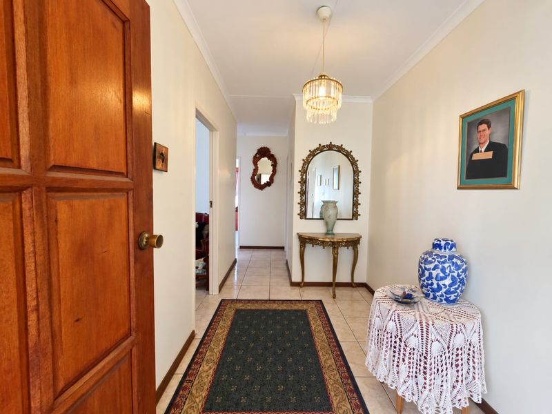 A bright and welcoming entrance hallway featuring tiled flooring, a classic pendant light fixture, and a solid timber door leading into the home.