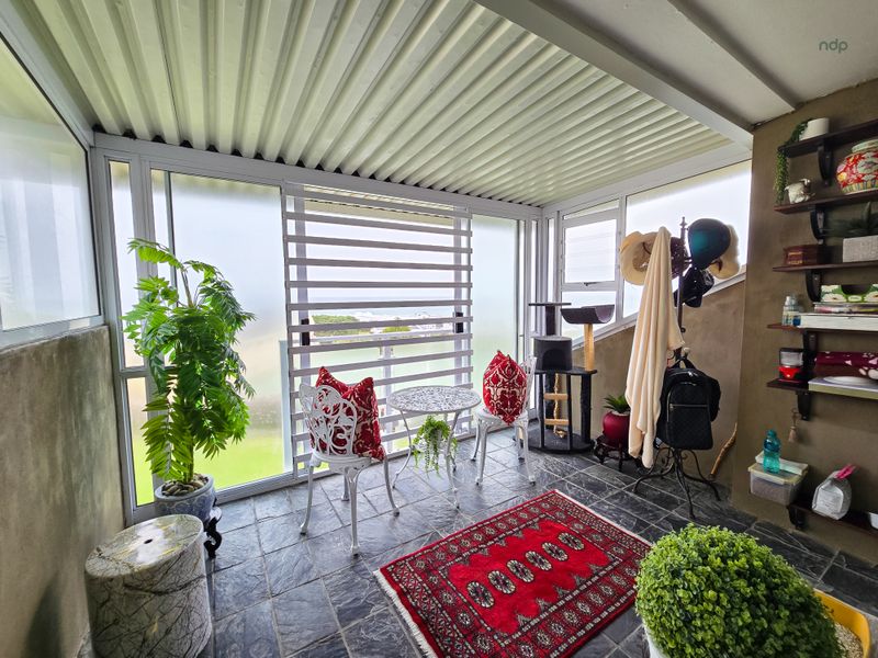 A covered patio area featuring slate tile flooring, corrugated metal roofing, and sliding glass doors, providing a versatile outdoor living space.