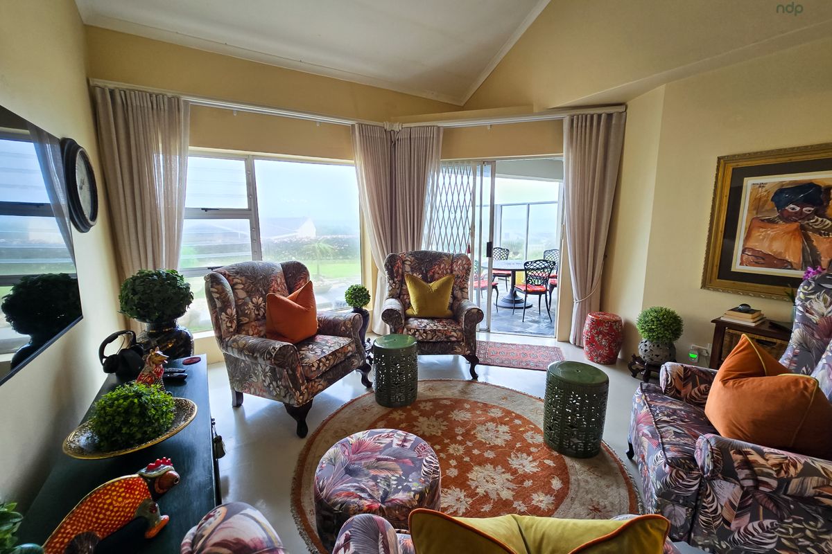 A comfortable living room featuring large windows and a sliding glass door that opens onto a patio, providing ample natural light.