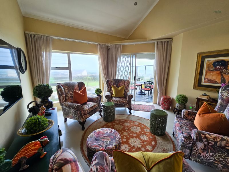 A comfortable living room featuring large windows and a sliding glass door that opens onto a patio, providing ample natural light.