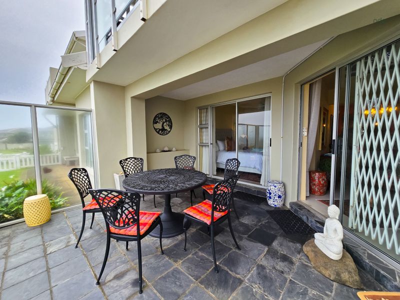 A covered outdoor patio featuring slate tile flooring and direct access to the interior through sliding glass doors.