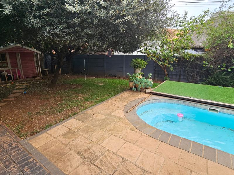 Outdoor pool area featuring a paved patio, swimming pool with cover, and a private garden with boundary walling.