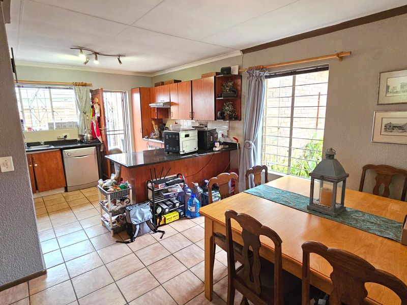 Open-plan kitchen and dining area featuring tiled flooring, built-in wooden cabinetry, and granite countertops, offering a functional layout for daily living.