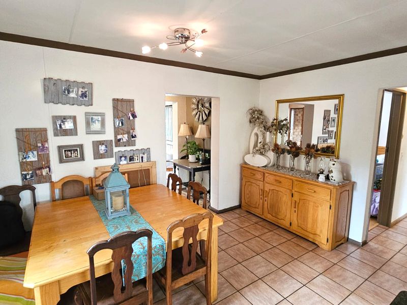 A dining room featuring tiled flooring and a central ceiling light fixture, with an open doorway leading to adjacent living spaces.