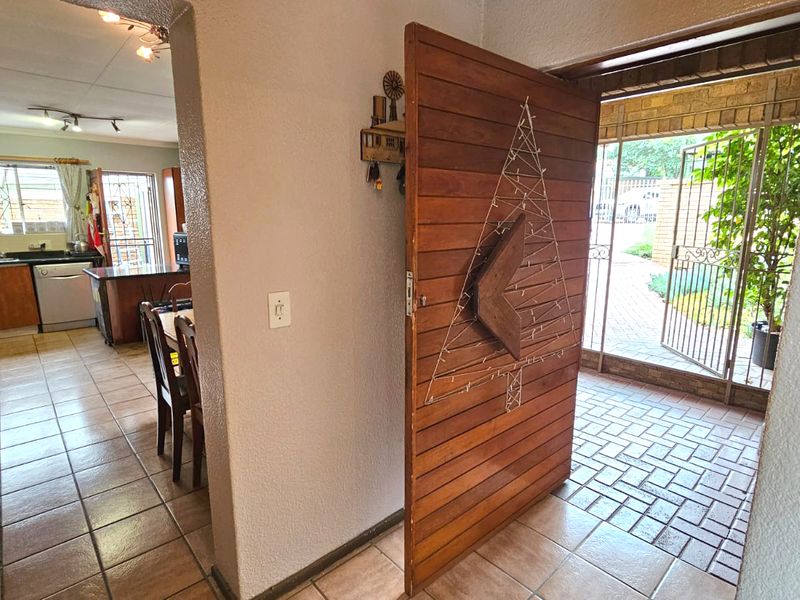Entrance area featuring a large wooden pivot door, tiled flooring, and a view through to the open-plan kitchen and dining space.