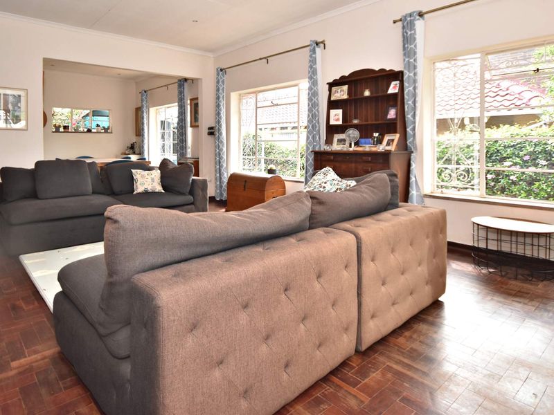 Spacious living room featuring classic parquet flooring and large windows that provide ample natural light, creating a warm and inviting atmosphere.