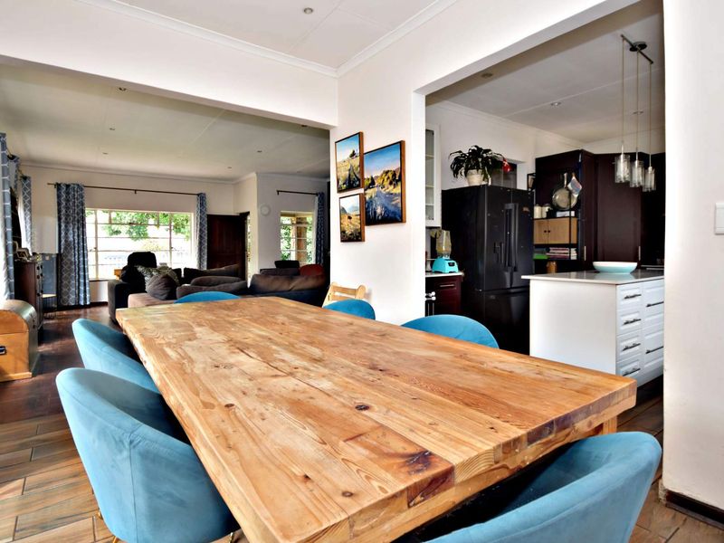 Spacious open-plan dining and kitchen area featuring a central island, tiled flooring, and recessed lighting, creating a functional and connected living space.