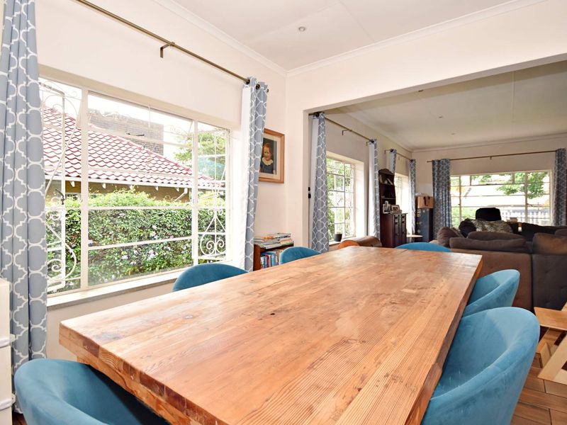 Spacious open-plan living and dining area featuring large windows with security bars, tiled flooring, and recessed ceiling lighting.