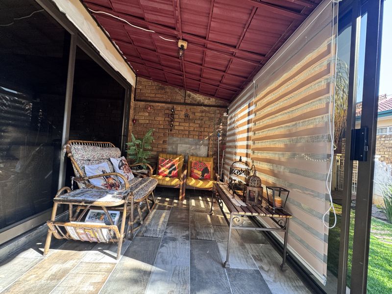 A covered patio area featuring exposed brick walls, tiled flooring, and sliding glass doors, providing a functional outdoor living space.