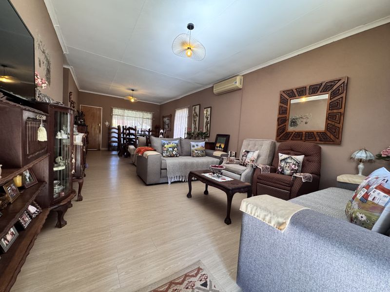 Spacious open-plan living and dining area featuring laminate flooring and a wall-mounted air conditioning unit.