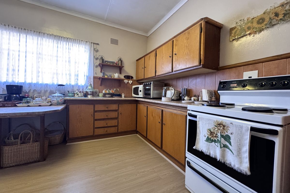 A functional kitchen featuring traditional wooden cabinetry, laminate countertops, and a tiled backsplash, offering a classic layout with potential for modern updates.