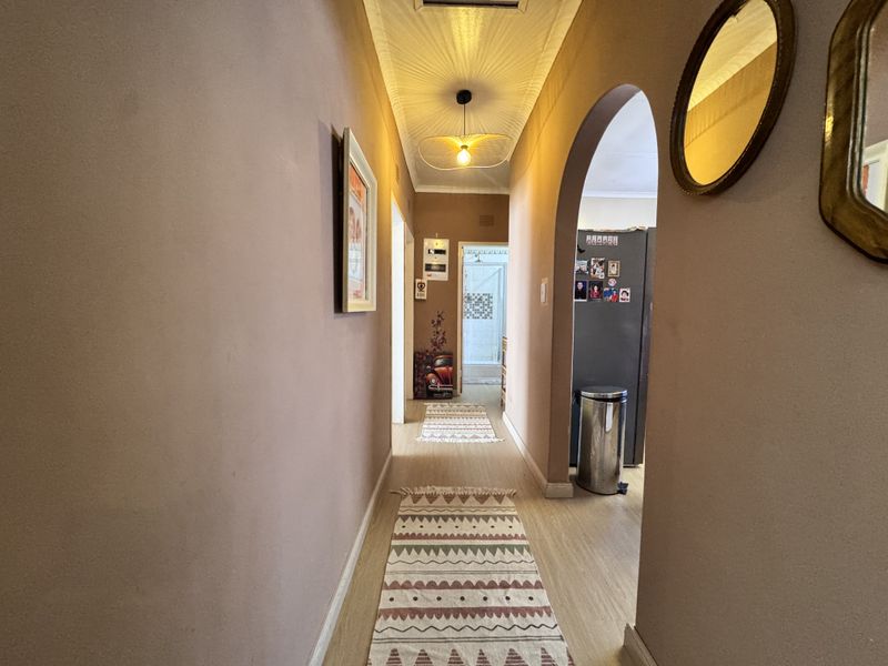 A functional hallway featuring an arched entryway, textured ceiling, and laminate flooring, providing access to adjacent living spaces.