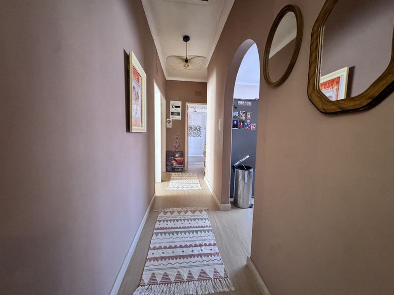 A well-lit interior hallway featuring an arched transition, laminate flooring, and a modern pendant light fixture, connecting various rooms within the townhouse.