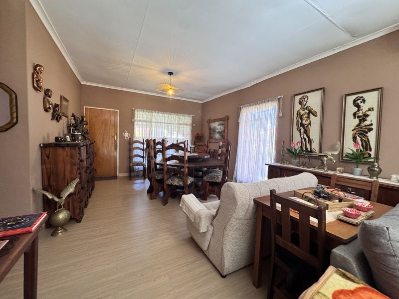 Open plan living and dining area featuring laminate flooring, coved ceilings, and access to the exterior via a sliding glass door.