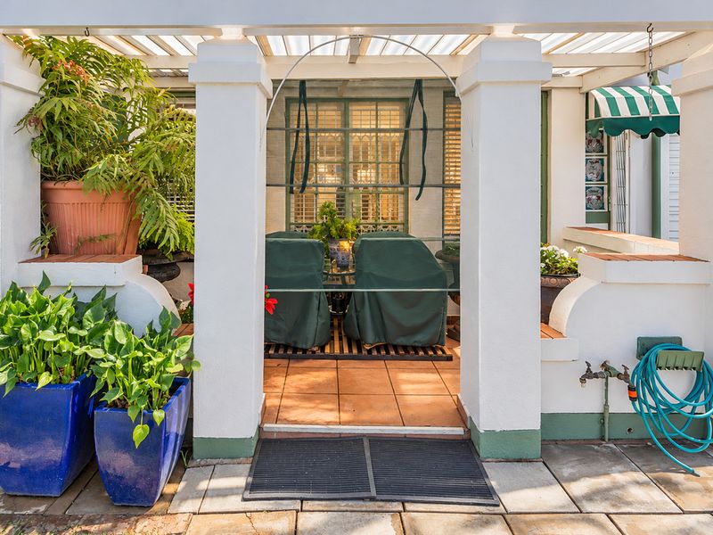 A covered patio area featuring tiled flooring, masonry pillars, and a pergola structure, providing a pleasant outdoor space for relaxation.