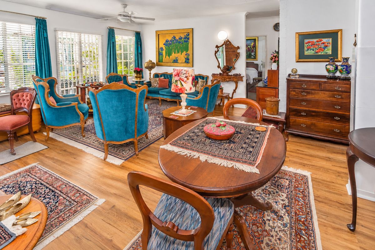 A spacious, well-maintained living area featuring laminate flooring, a ceiling fan, and large sliding glass doors that provide ample natural light.
