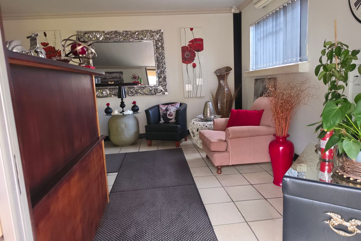 A living area featuring tiled flooring, a wall-mounted air conditioning unit, and vertical blinds, providing a functional space with neutral wall finishes.