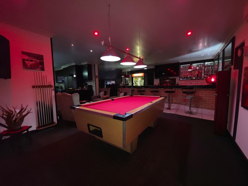 A dedicated entertainment bar area featuring a built-in brick counter, recessed lighting, and pendant fixtures, creating a functional space for social gatherings.