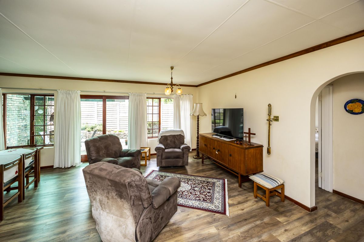 A comfortable living room featuring laminate flooring, an arched entryway, and sliding glass doors that provide access to the outdoor area.